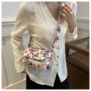 Detail of crossbody bag with colorful butterfly prints worn with a casual outfit