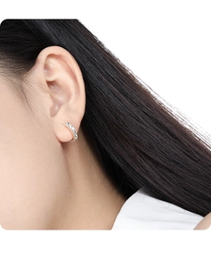 Close-up of minimalist silver hoop earrings featuring an intricate carved diamond pattern