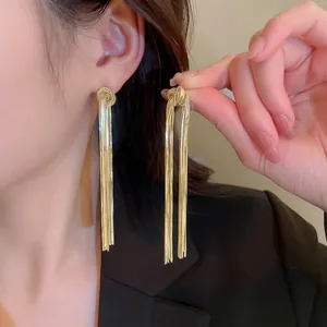 Elegant gold-tone tassel knot earrings with long snake chains on fashion model