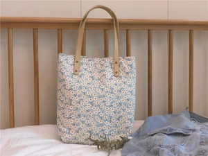 Détail du sac cabas floral en toile avec poignées en cuir renforcées et rivets