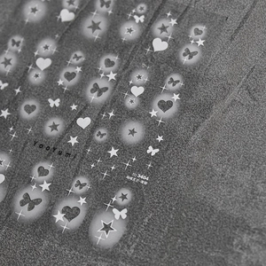 Detailed close-up of thin adhesive nail stickers featuring white butterfly and star patterns