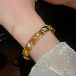 Detailed close-up of gold-plated bangle with white mother of pearl clover patterns