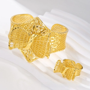 Detail of gold hollowed cuff bracelet and ring set with intricate bowknot patterns