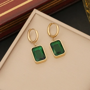 Golden hoop earrings with emerald green rectangular pendant on a vintage jewelry display