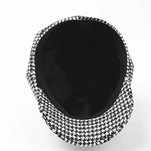 Detail view of the houndstooth baker boy hat featuring black lining and sweatband