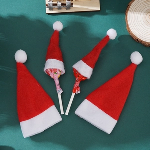Close-up of four mini red felt Santa hats with white plush trim on green background