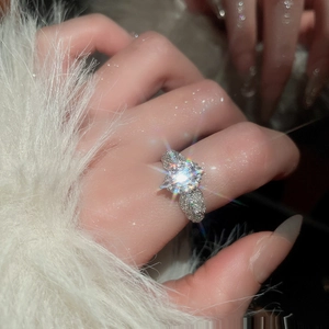 Detail of silver zircon flower ring with full pavé stones on a finger in dark setting