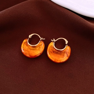 Detail of amber resin vintage hoop earrings with 18k gold plating on a brown fabric