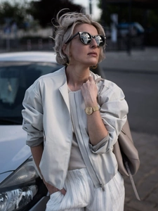 Women's cream faux leather bomber jacket styled with white striped trousers and watch
