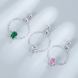 Detail of adjustable silver chain rings with emerald, pink, and clear oval-cut stones