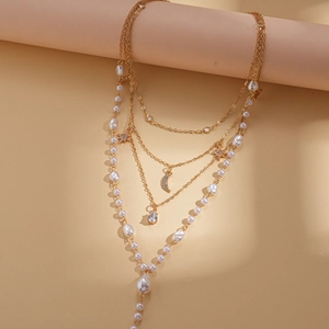Detailed view of multilayer gold necklace with star and moon charms and baroque pearls
