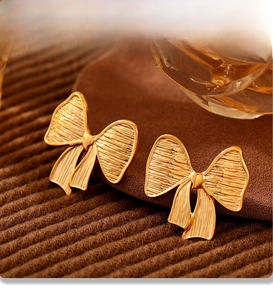 Macro view of gold bow earrings with PVD plating texture on brown velvet