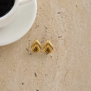 Détail de boucles d'oreilles cœur dorées avec texture nervurée sur fond en pierre naturelle