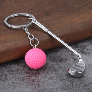 Pink golf ball and silver metal club keychain pendant displayed on a textured surface
