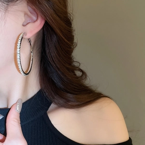 Close-up of a model wearing large silver hoop earrings paved with shiny crystals