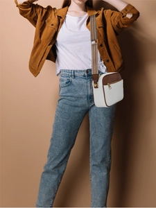 Detail of a brown quilted crossbody bag featuring V-shaped stitching and jacquard strap