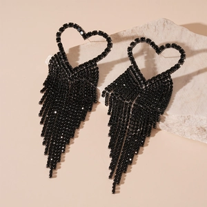 Close-up of black heart earrings with sparkling tassel fringe on natural stone