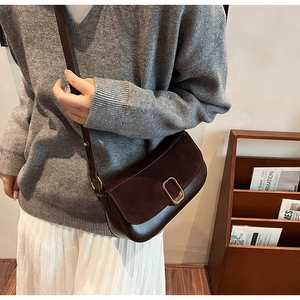 Detail of dark brown vintage saddle bag featuring suede panel and gold buckle