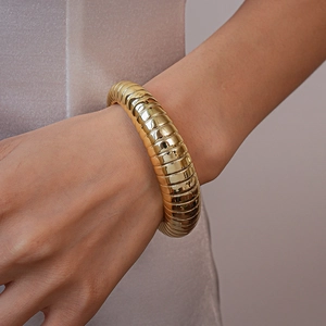 Close-up of golden ribbed cuff bracelet with a polished metallic finish on a female wrist
