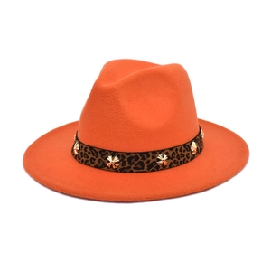 Macro detail of orange wool fedora featuring leopard print band and golden cross studs