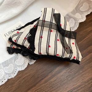 Close-up of heart print fabric and delicate black lace trim with mesh bow detail