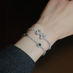 Close-up of sparkling bow bracelet and emerald green zircon bangle on model's wrist
