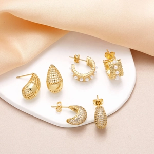 Elegant gold-plated teardrop earrings set with cubic zirconia and pearls on satin