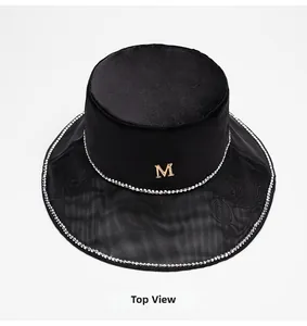 Top view of black satin bucket hat featuring a mesh brim and gold M logo detail