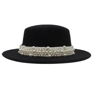 Detailed view of large white pearls on a vintage black wool felt boater hat