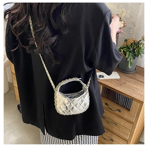 Detail view of mini quilted metallic silver crescent bag with golden chain strap on model