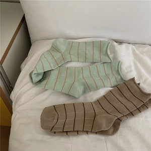 Detailed view of Morandi green and brown plaid socks made of soft cotton on a white bed