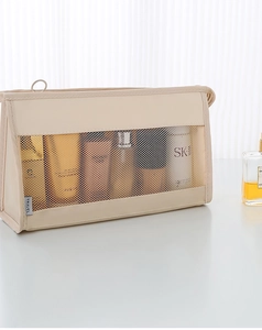 Detail of beige travel toiletry bag featuring breathable nylon mesh and TRAVEL woven label