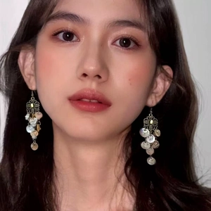 Detail showing vintage silver bow earrings with layered pearl tassels worn by a model