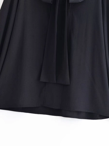 Detailed close-up of a black long-sleeved shirt featuring elegant ribbon ties and hem