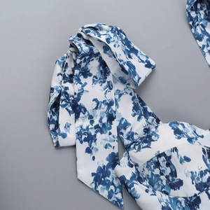 Détail de l'épaule à nœud et de l'imprimé floral bleu sur une robe d'été blanche