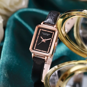 Detail of rectangular rose gold watch with black leather strap on green silk background