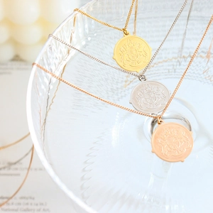Trois colliers avec pendentifs pièces ronds en or, argent et or rose avec blason