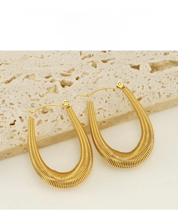 Macro detail of gold U-shaped spring textured earrings with polished finish and push-back clasp