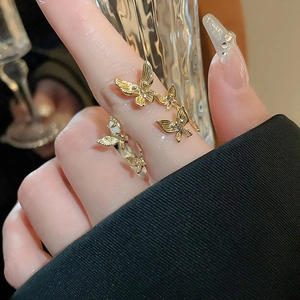 Close-up of gold-plated butterfly ring with pearls on a model hand with soft lighting