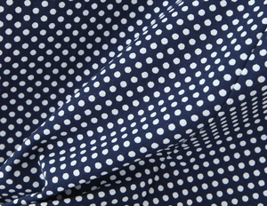Detailed view of the dark blue fabric with white polka dots and soft texture