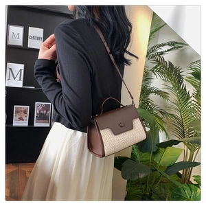 Détail du sac bandoulière en similicuir marron et paille porté par un mannequin