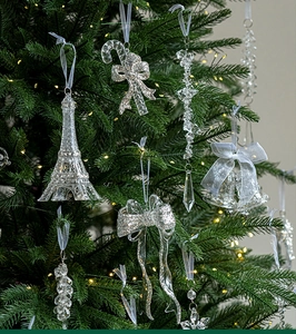 Macro shot of glittery Christmas tree ornaments with warm string lights on branches