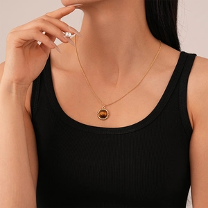 Vintage gold necklace with round tiger eye stone pendant worn on a female model