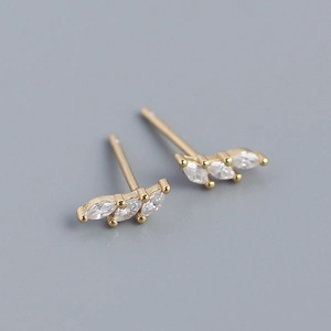 Detailed close-up of gold stud earrings featuring three marquise-cut clear zircons
