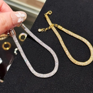 Close-up of gold and silver mesh bracelets with sparkling zircons and lobster clasp