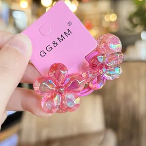 Pair of pink camellia elastic hair ties with iridescent petals on a branded card