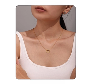 Dettaglio della collana con ciondolo a cuore dorato e catena sottile su modella