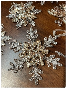 Macro shot of acrylic snowflake ornaments with champagne gold sequins on wooden background