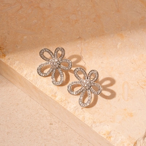 Detailed view of silver hollow flower earrings with zircons on a natural stone base