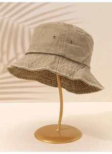 Détail d'un chapeau bob en denim lavé kaki sur un support en métal doré
